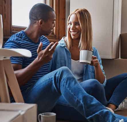 Young couple siting in their new house surrounded buy moving boxes.