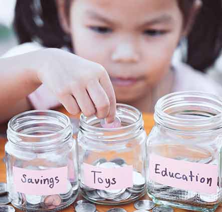 Young girl putting money in savings jars.